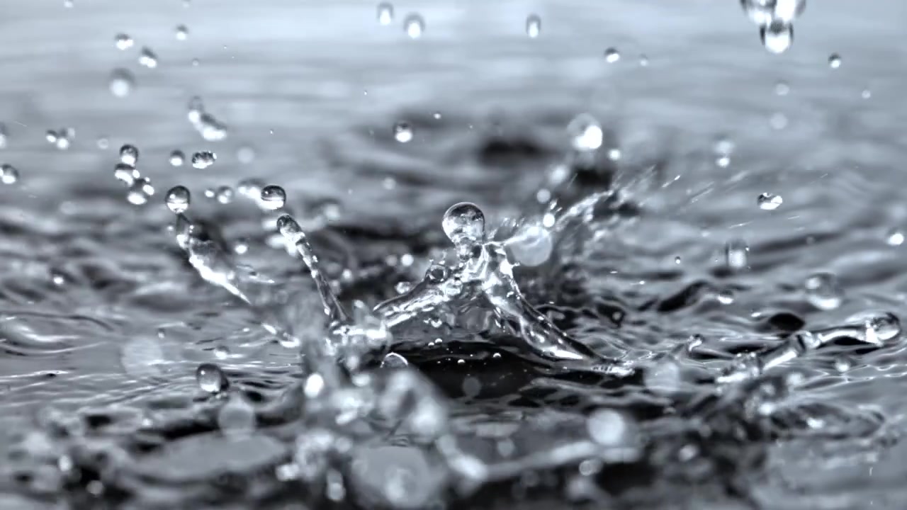 Zeitlupe: Wassertropfen spritzen auf eine flüssige Oberfläche