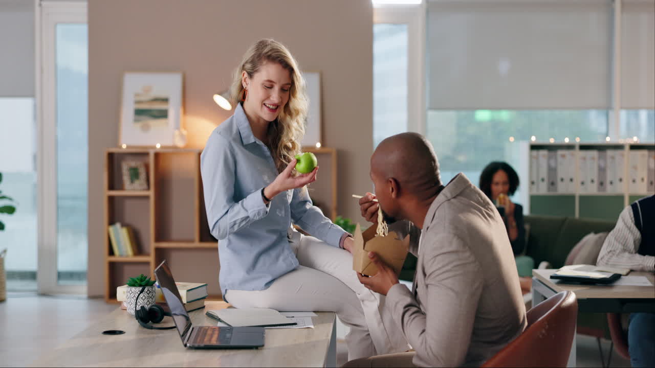 Two colleagues eating lunch at their desks in an office