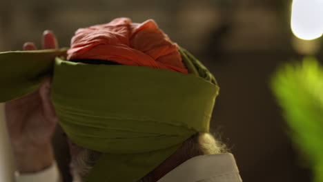 fotografía de estudio de un anciano sikh con barba atando tela para un turbante contra un fondo plano tomada en tiempo real 3