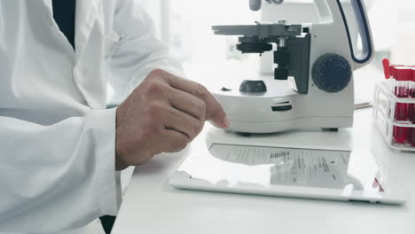 scientist using microscope and tablet in laboratory