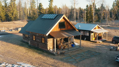 aerial orbit around log cabin house in a snowy forest field