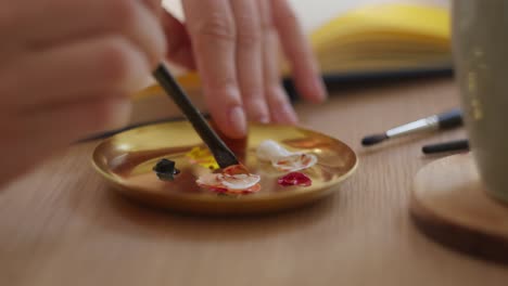 artist hands mixing color on palette, close up