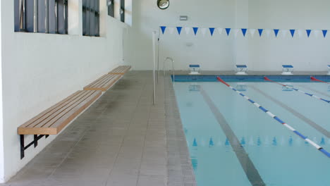 An-indoor-swimming-pool-awaits-swimmers,-with-copy-space