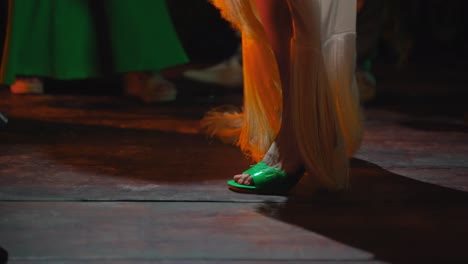 close up of woman's feet dancing in long white dress on a club venue dance floor with colorful strobe lights flashing during night time