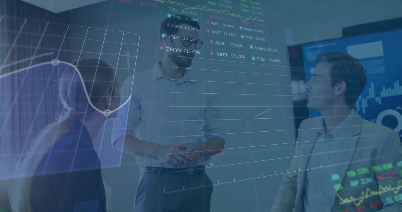 Standing presenter speaking, holding cup, activating finance charts over room colleagues reviewing