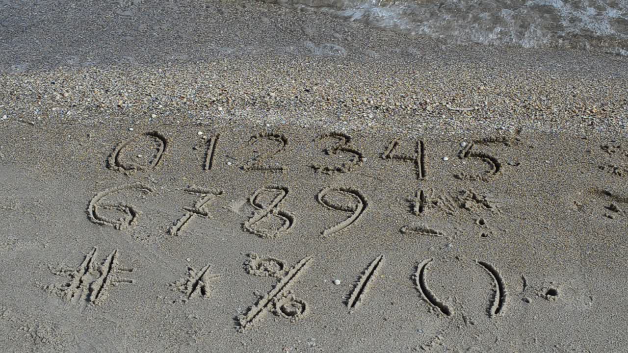 Cijfers en tekens geschreven in strandzand. Strandopname.