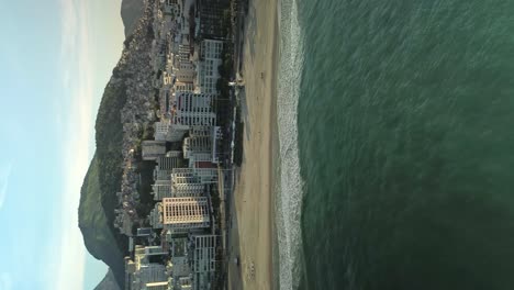 Playa-De-Arena-Y-Paisaje-Urbano-De-Río-De-Janeiro---Retroceso-Aéreo,-Vídeo-Vertical