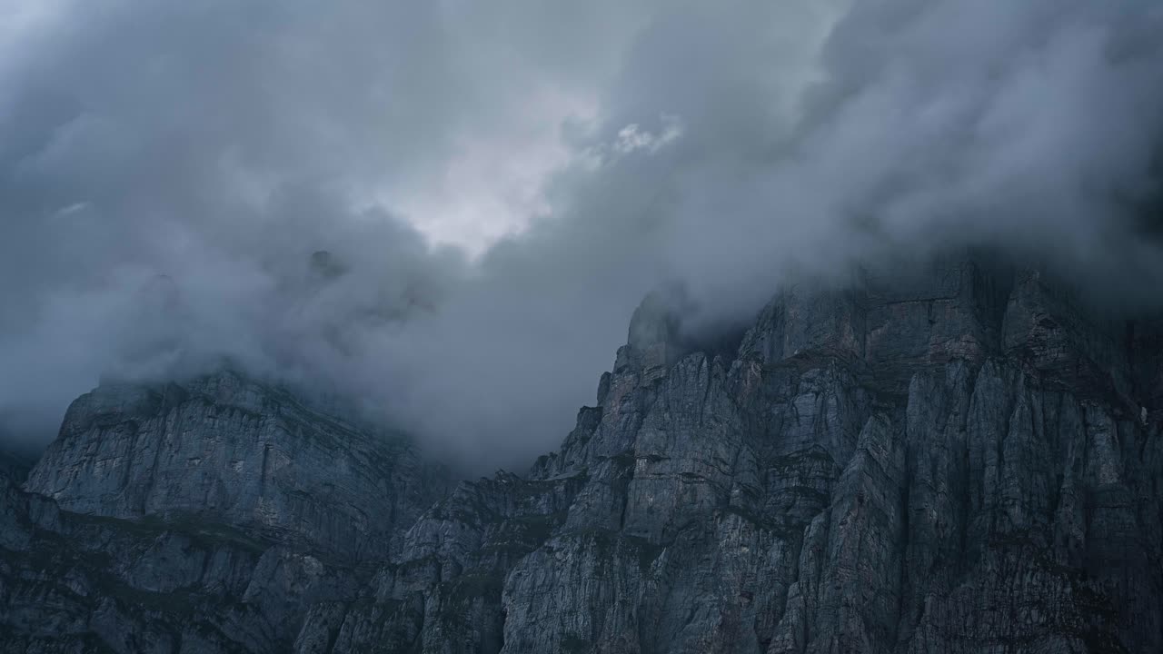 las nubes se elevan a lo largo del paso de klausen mientras la luz del sol baila en los acantilados de granito de urnerboden, suiza.