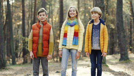 joyful kids, girl and two boys, smiling at camera in the forest on a sunny day