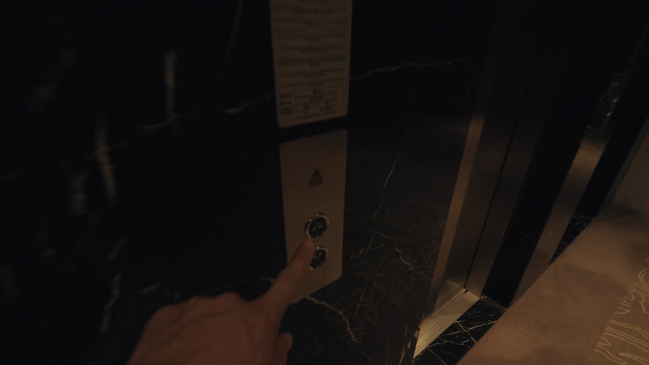 hombre caminando por el corredor del hotel y llamando al ascensor