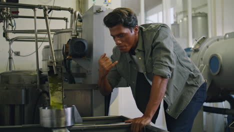 professional guy tasting olive oil at factory close up. man controlling process