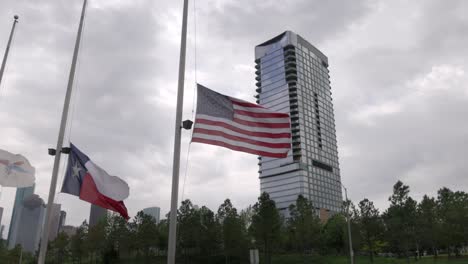 american flag and texas state flag flying in the wind with gimbal video walking forward