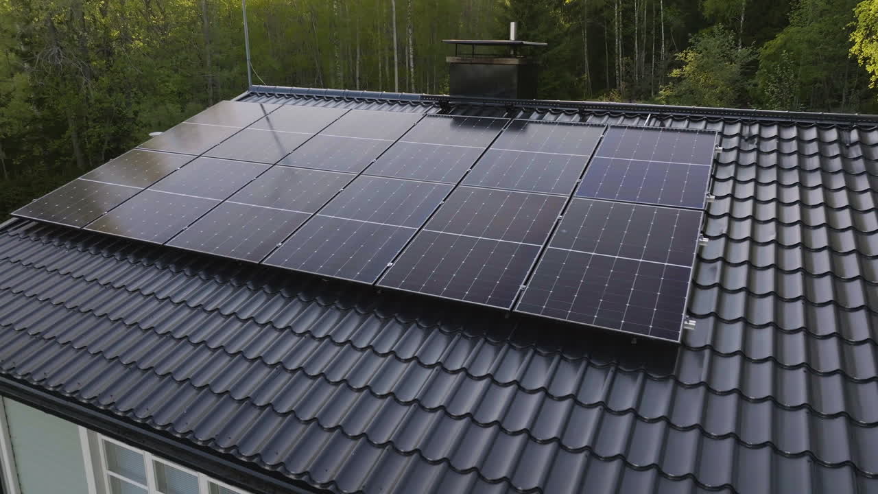 Aerial view of solar power modules on a private house roof, summer evening