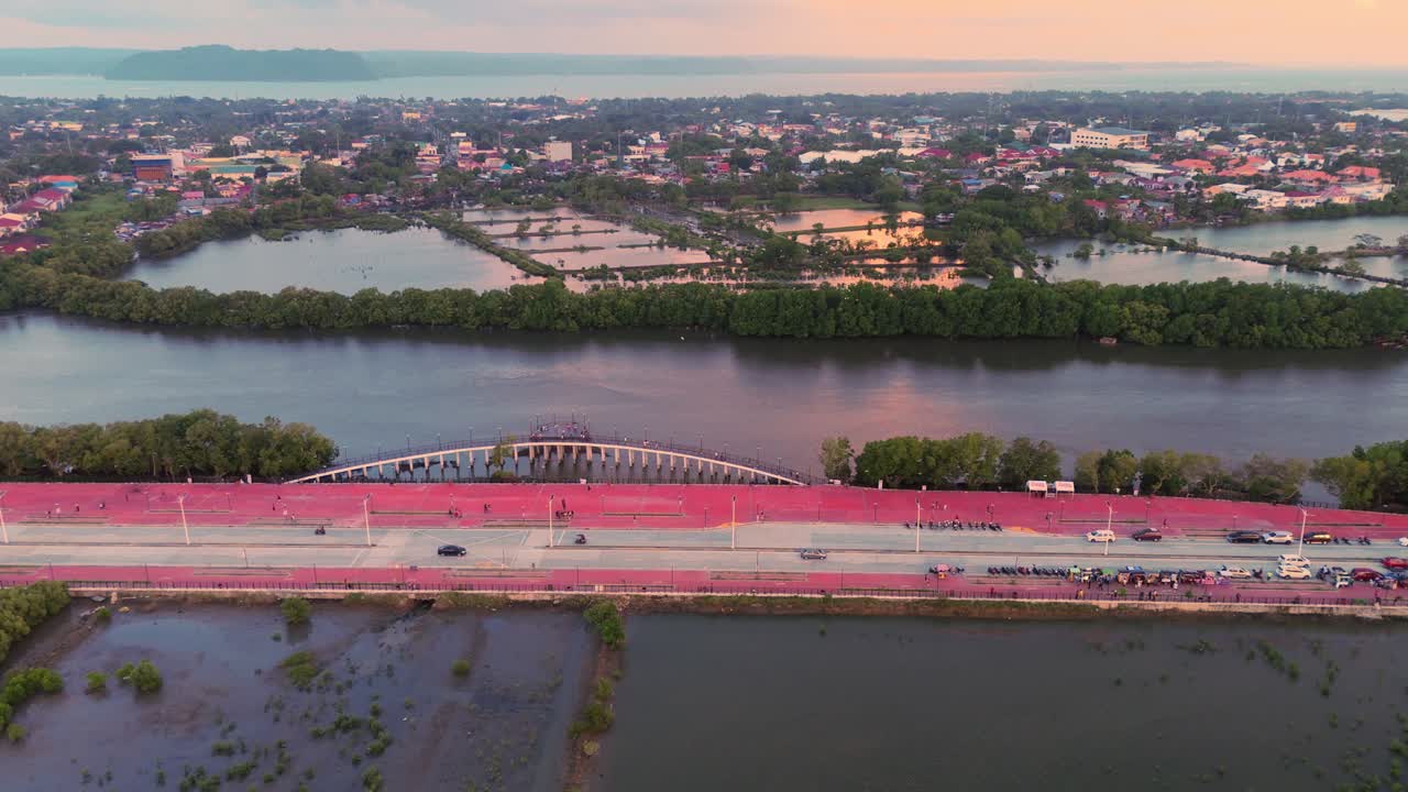 Wide aerial of a city with wetlands, mangroves, and a waterfront bridge during sunset in the Philippines. Perfect for travel, urban, and environmental projects