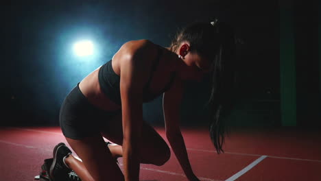 atleta femenina en un fondo oscuro para correr el sprint de la almohadilla de cross country en la cinta de correr en un fondo oscuro