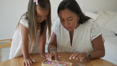 mother and daughter beading together