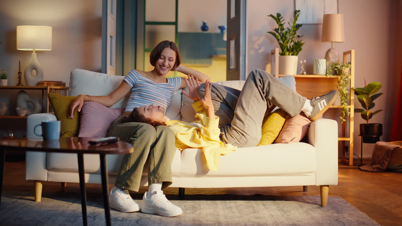 Lesbisk par slapper af på sofaen og nyder ubesværet kommunikation. Smilende kvinde