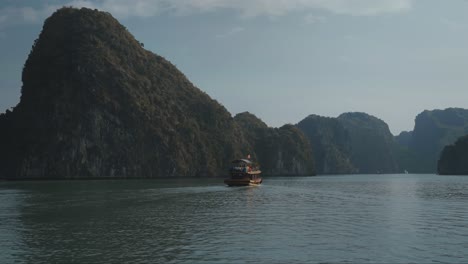 Traditional-Fishing-Boat-Sailing-Towards-Limestone-Cliffs-In-Lan-Ha-Bay,-Vietnam