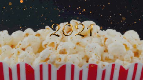 Animation-of-2021-over-popcorn-on-black-background