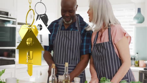 animation of gold house key over diverse couple smiling in kitchen