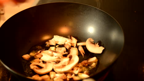 frying champignons in a black wok