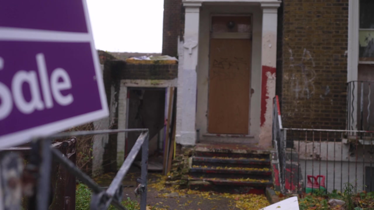 Un cartello viola "Vendesi" si trova davanti a una casa abbandonata a Londra, circondata da rifiuti e in grave stato di degrado.
