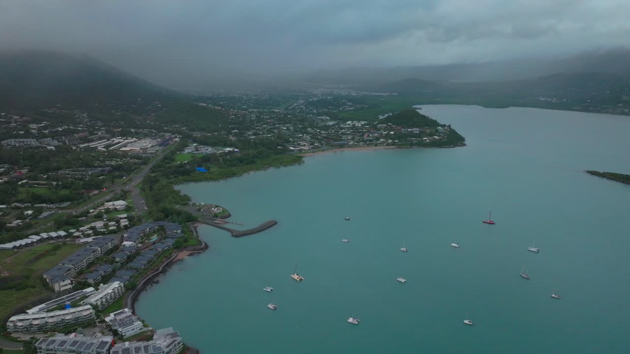 lluvioso puerto airlie playa bahía laguna mar de coral marina drone aéreo carretera coches hacia cannonvale rosa amarillo amanecer corazón de la gran barrera de arrecifes whitsundayshaven barcos blancos hacia atrás