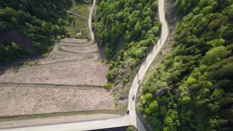 Luftaufnahme-Von-Oben-Nach-Unten-Von-Autos,-Die-Auf-Der-Straße-Entlang-Des-Stausees-Mit-Bäumen-Im-Vordergrund-Fahren