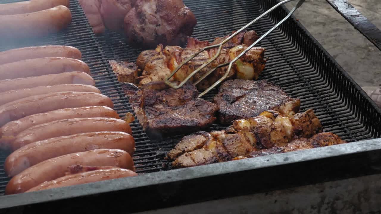 Man turns over the meat on the grill. He work outside.