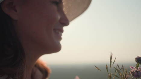 close up of young woman hand tightly holding wildflowers with morning sunlight casting soft glow over petals and fingers, creating serene and earthy mood in calm natural environment