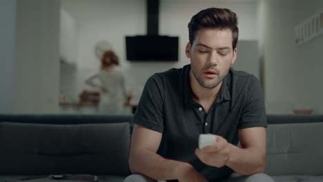 Handsome-man-looking-for-tv-program-at-kitchen.-Smiling-guy-making-win-gesture