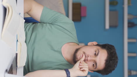 Vertical-video-of-Male-student-stressed-and-biting-his-nails.