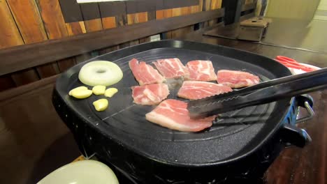 cooking samgyeopsal, a korean food composed of pork belly, onions, garlic