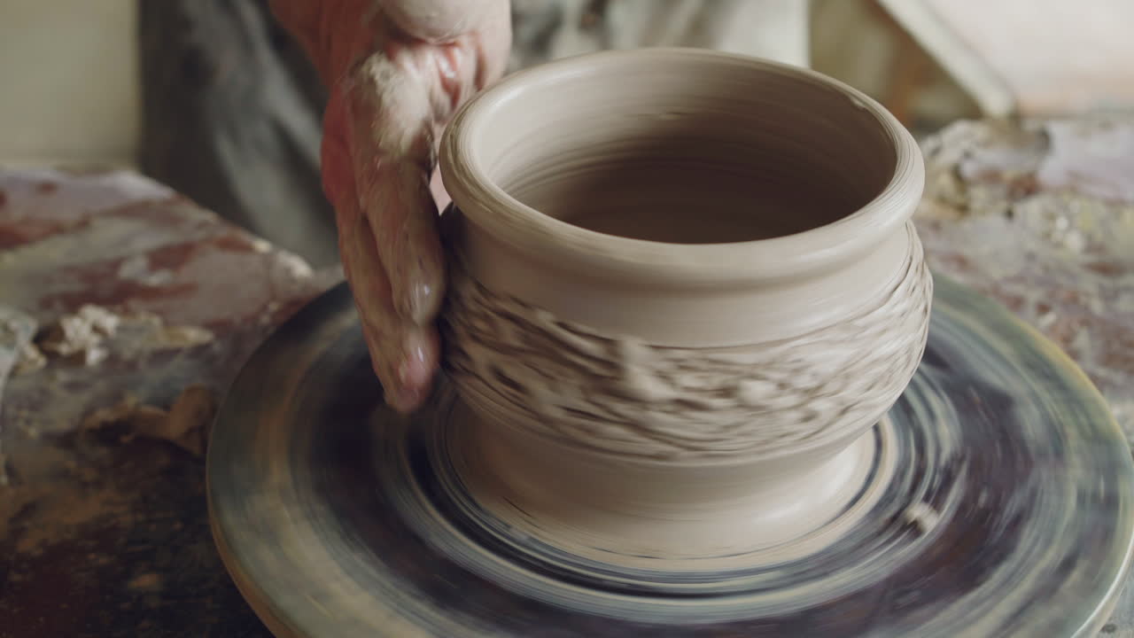 manos moldeando arcilla en una rueda de cerámica