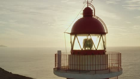 primer plano de un faro con el sol y el océano en el fondo a la hora dorada