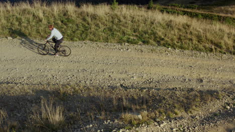 Mountain-bike-riding-drone-view-rocky-grassy-path-warm-sunny-summer-day-vacation