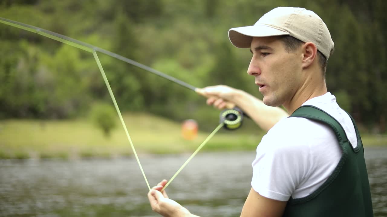 Rekaman Gerak Lambat seorang nelayan pria Kaukasia melempar kailnya saat Fly Fishing