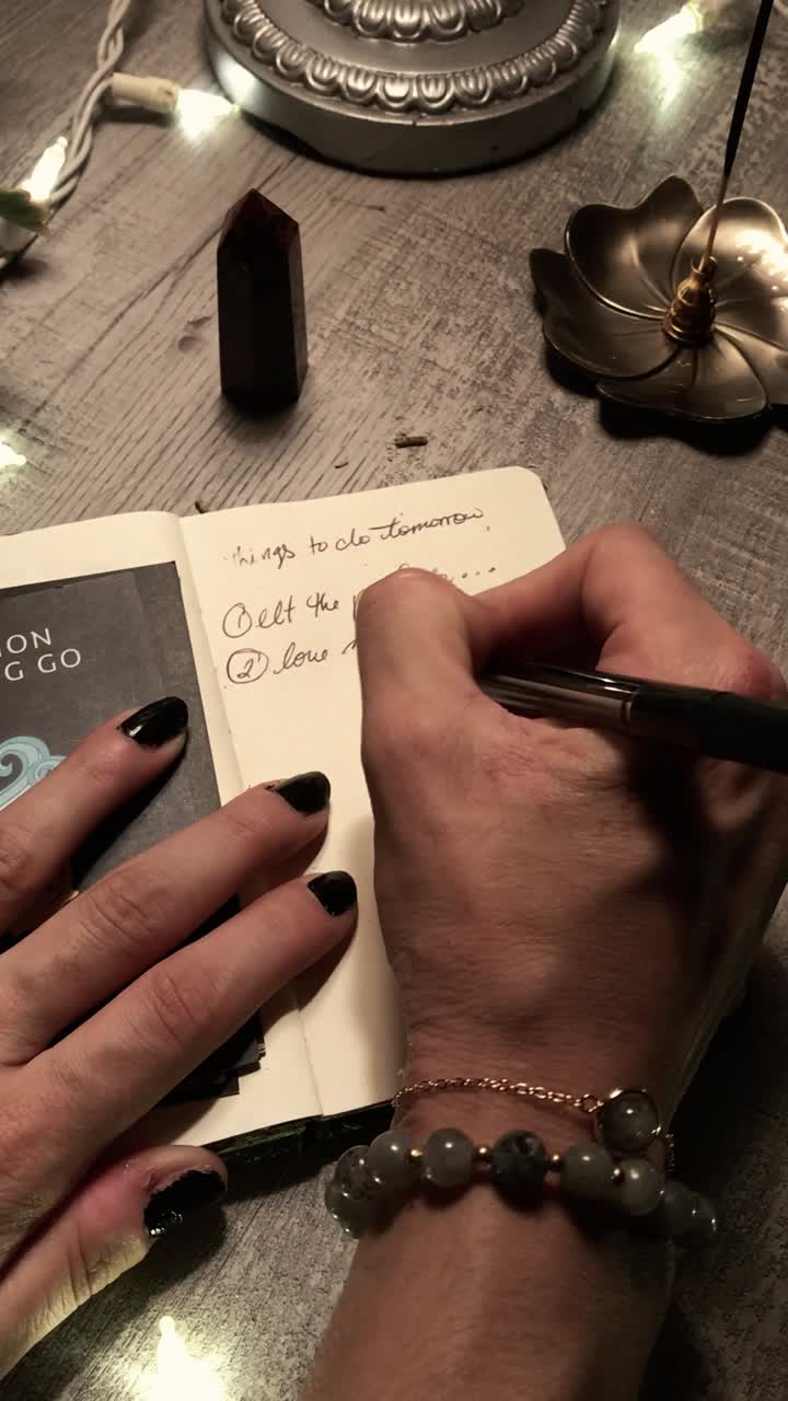 Person Writing in a Journal with Crystals and Other Spiritual Items