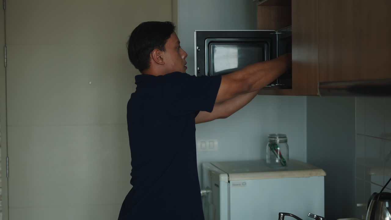 Uomo che usa il microonde in cucina