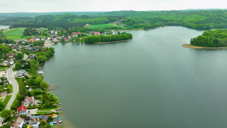 Una-Vista-Aérea-De-Una-Ciudad-Junto-Al-Lago-Con-Casas-A-Orillas-Del-Agua-Y-Exuberantes-Colinas-Verdes-Al-Fondo