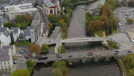 Cinematic-aerial-reveals-rush-hour-traffic-on-a-bridge-and-focuses-on-a-pedestrian-bridge-parallel-to-it