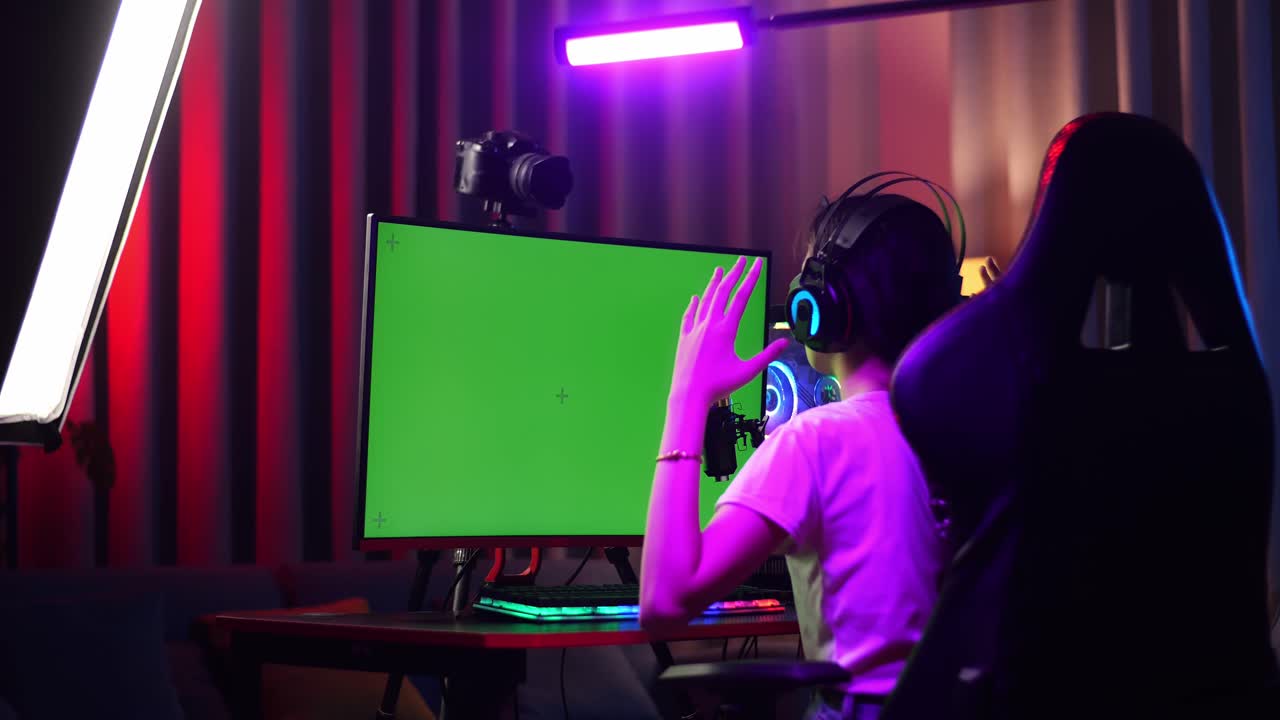 Back View Of Asian Girl Streamer Feeling Disappointed Fails Game Over On Green Screen Computer. Live Stream On Desk Illuminated By Rgb Led Strip Light