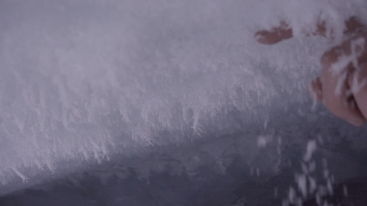 A person scrapes snow crystals and peels them off with his hand, cave in the swiss alps
