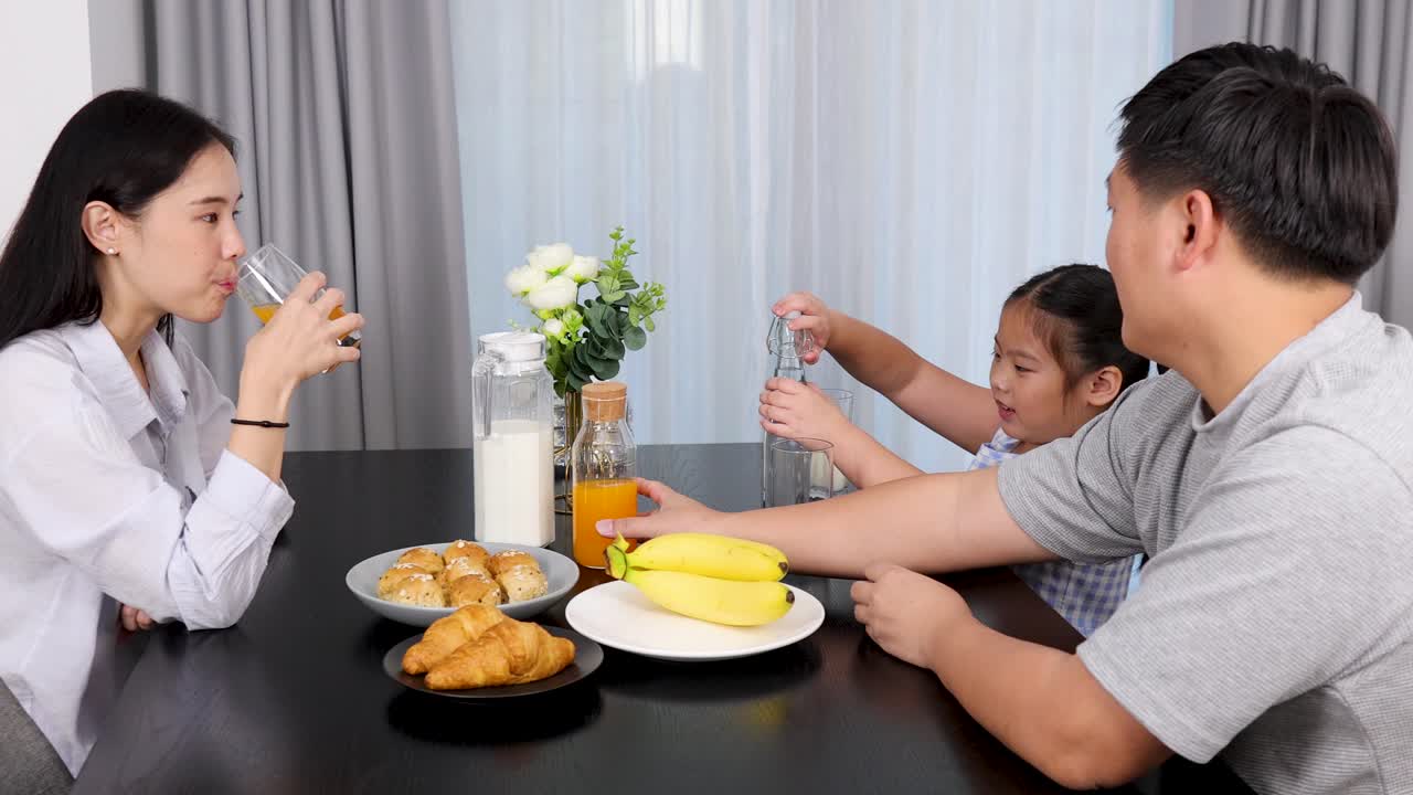 A family enjoys breakfast together, sharing orange juice and smiles in a bright, cozy dining setting