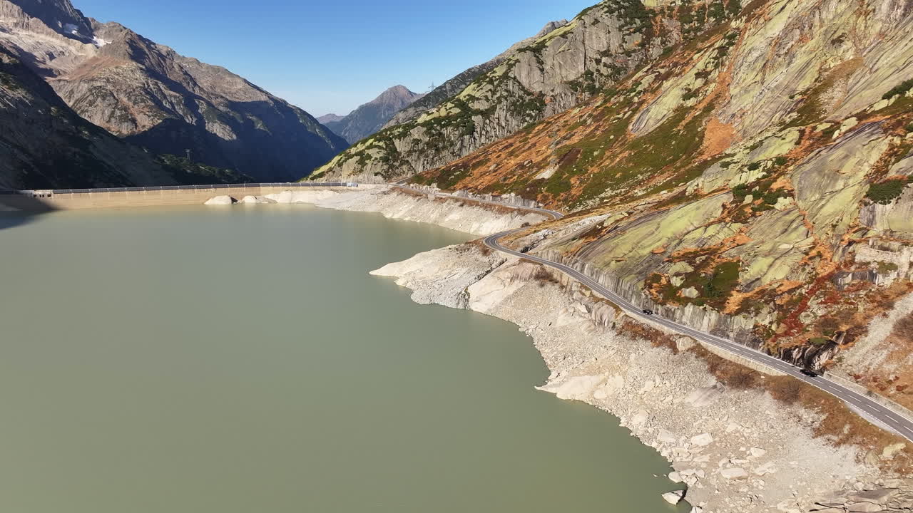 Grimsel water reservoir and mountain pass road on a sunny day with scenic views from above