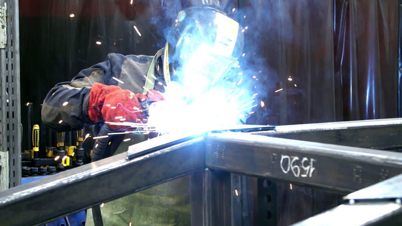 Welder with torch and protective helmet making bright sparks during welding