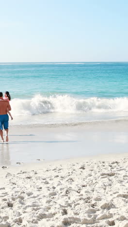 tres generaciones sonrientes de la familia corriendo hacia el mar