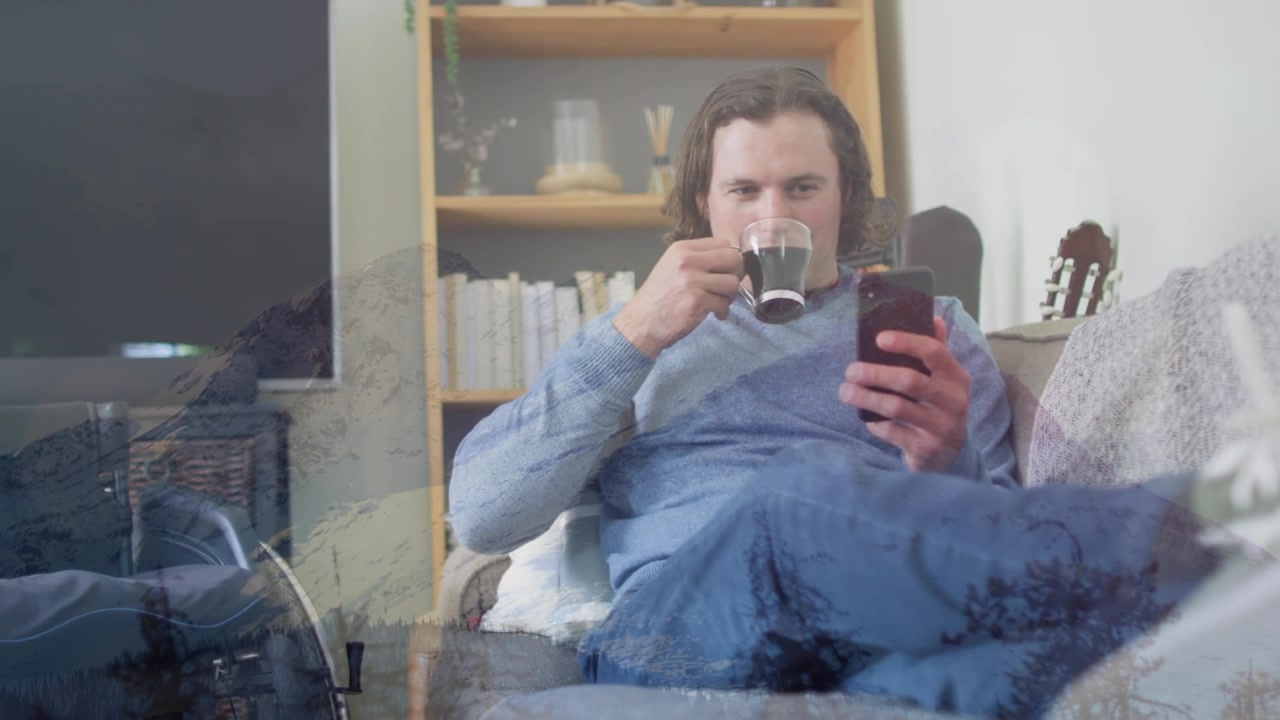 Animation of winter landscape over caucasian man using smartphone and drinking coffee