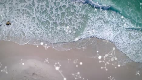 Digital-composition-of-molecular-structures-floating-against-aerial-view-of-the-beach