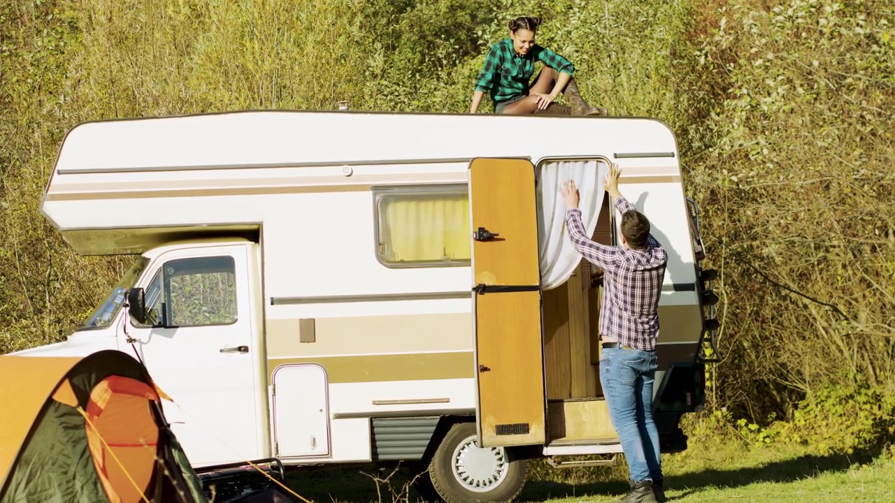Homem cumprimenta sua parceira descansando sobre o trailer
